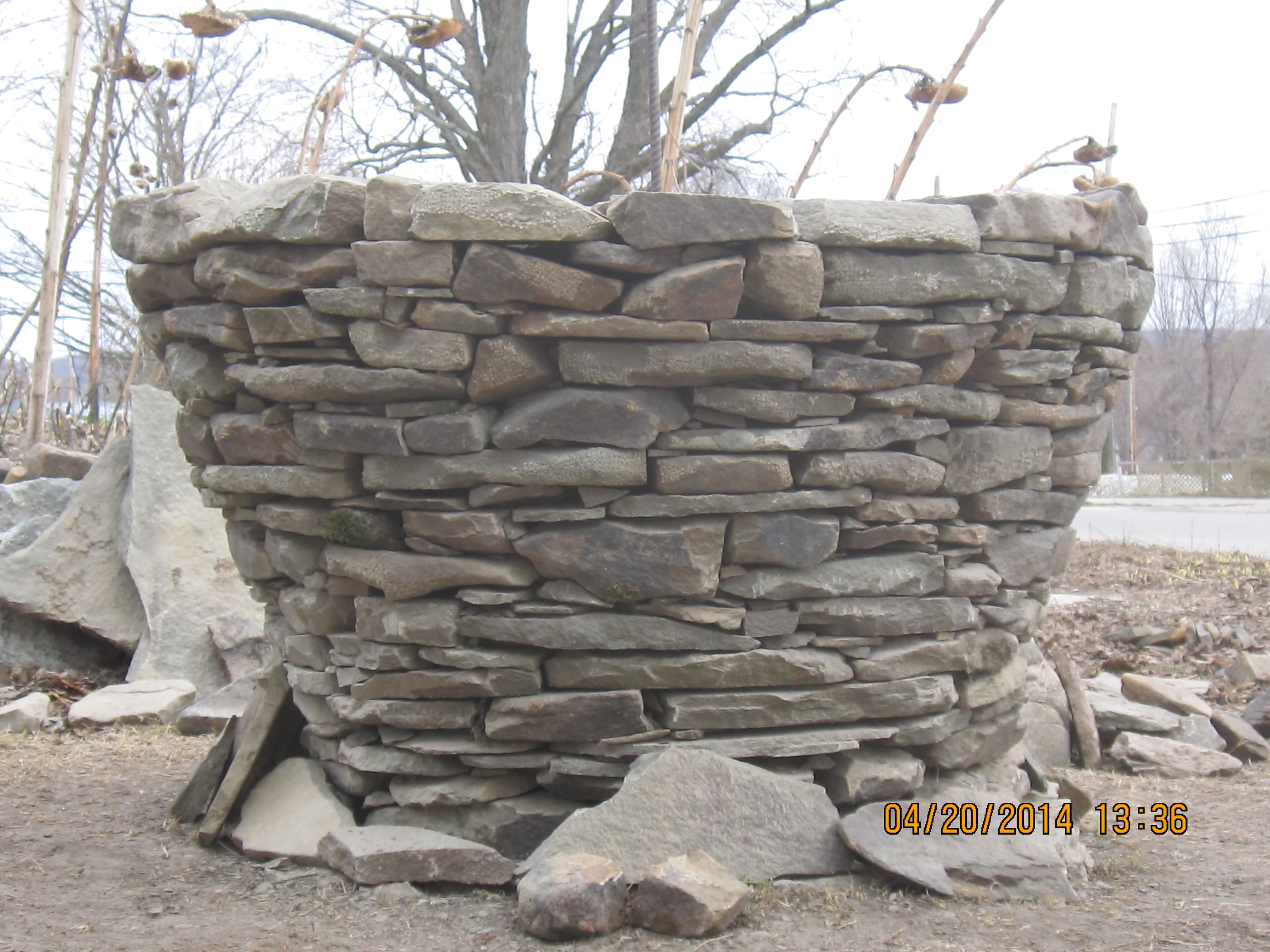 A large flower-pot-shaped dry stone form under construction.