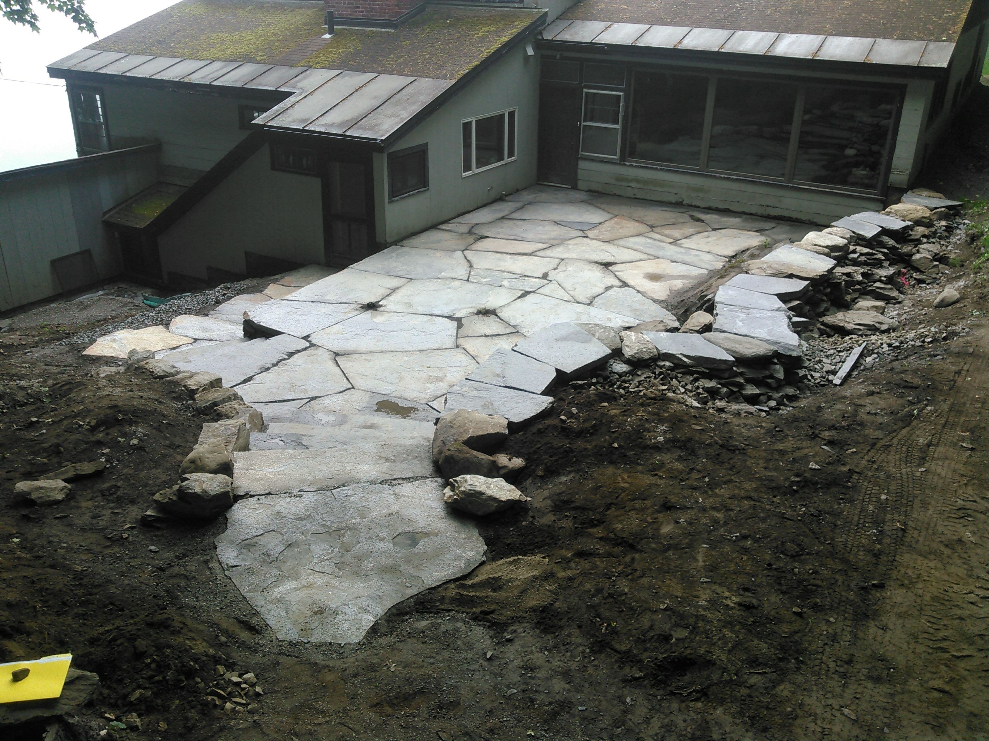 Flagstone terrace being laid behind a house.