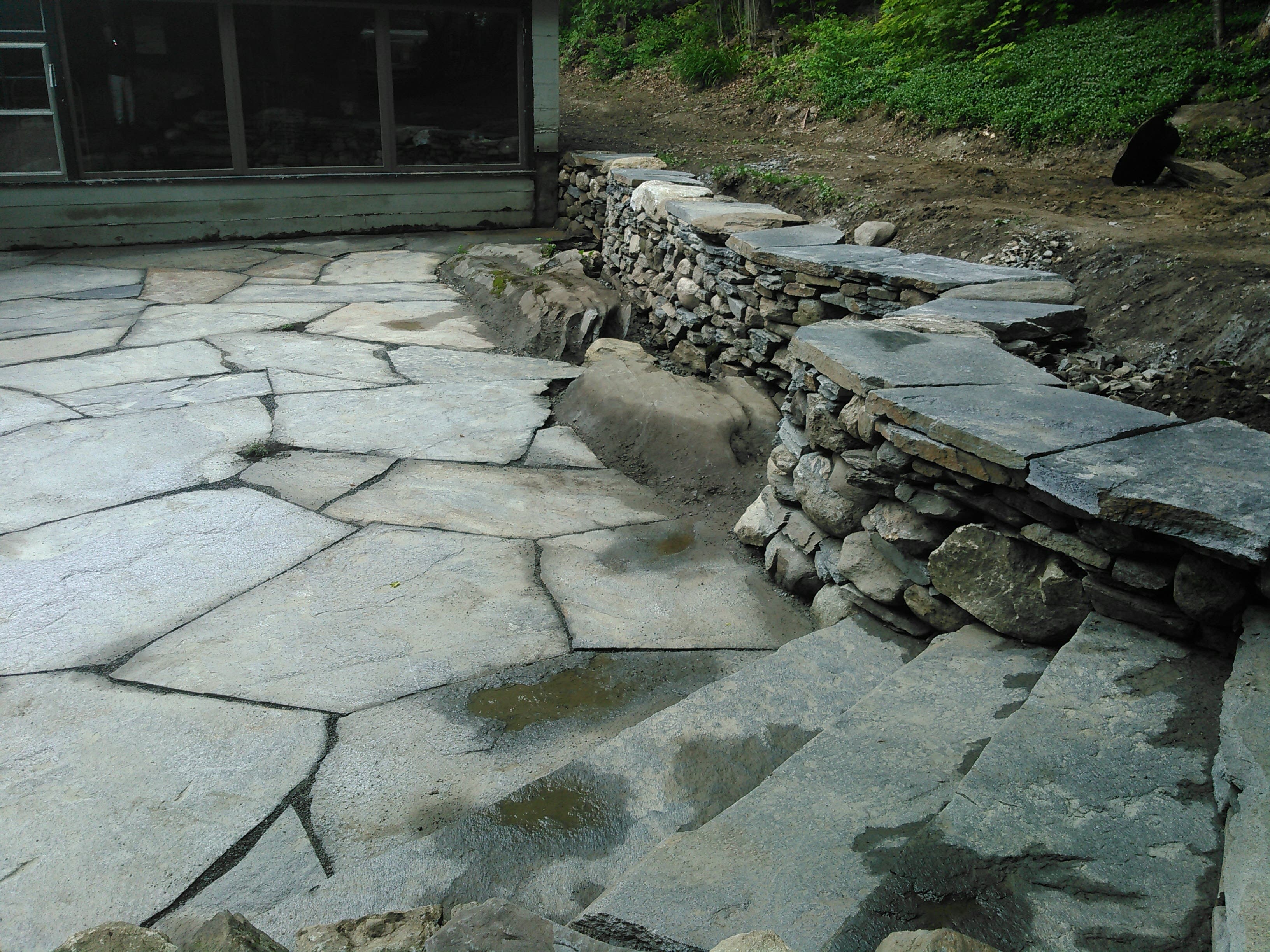 Flagstone terrace meeting a low dry stone retaining wall.