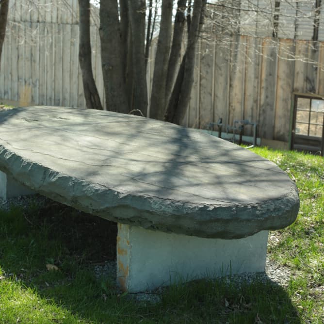 Long elliptical bluestone bench on limestone legs.
