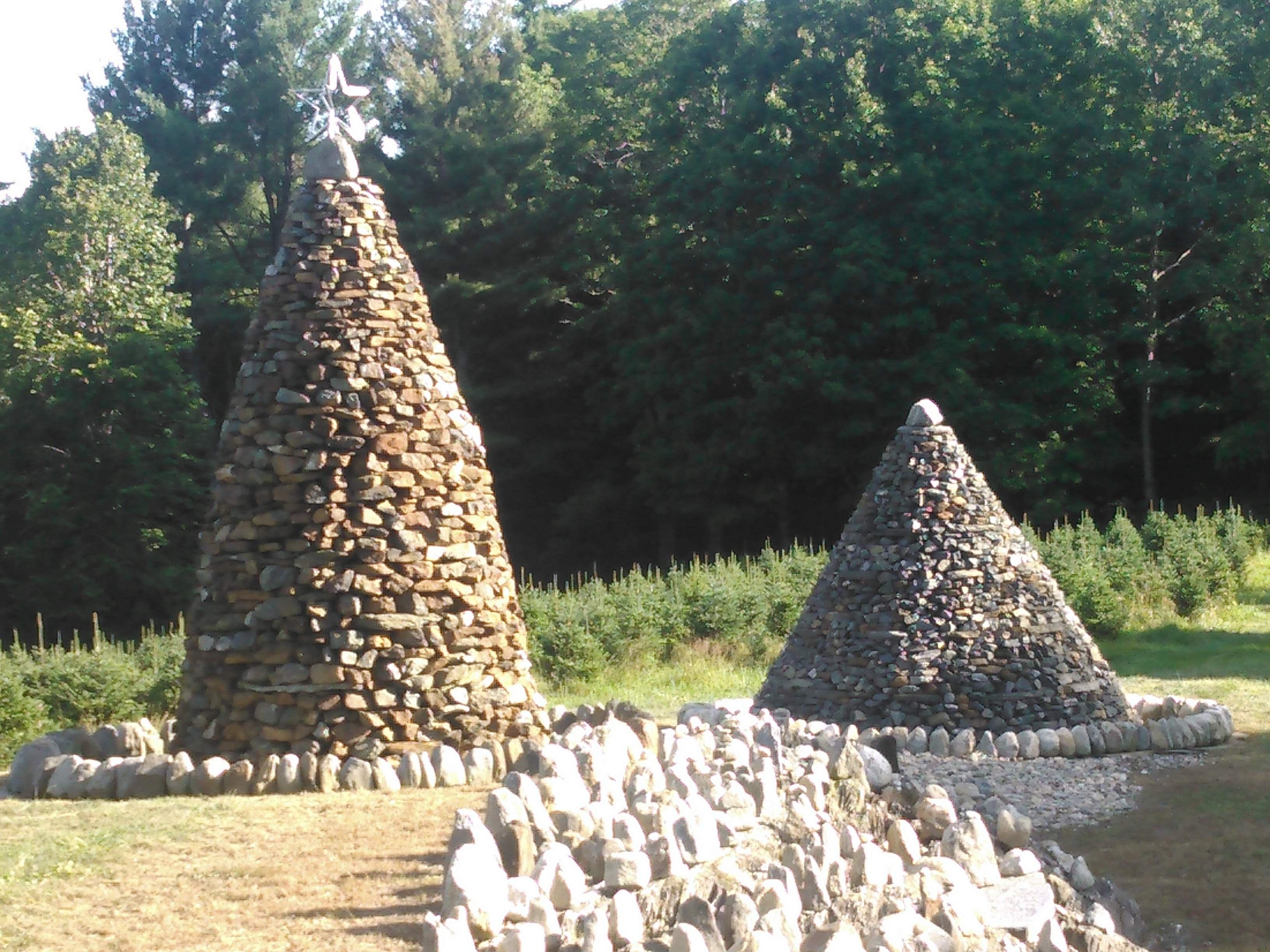Two tall conical dry stone cairns standing in a field.