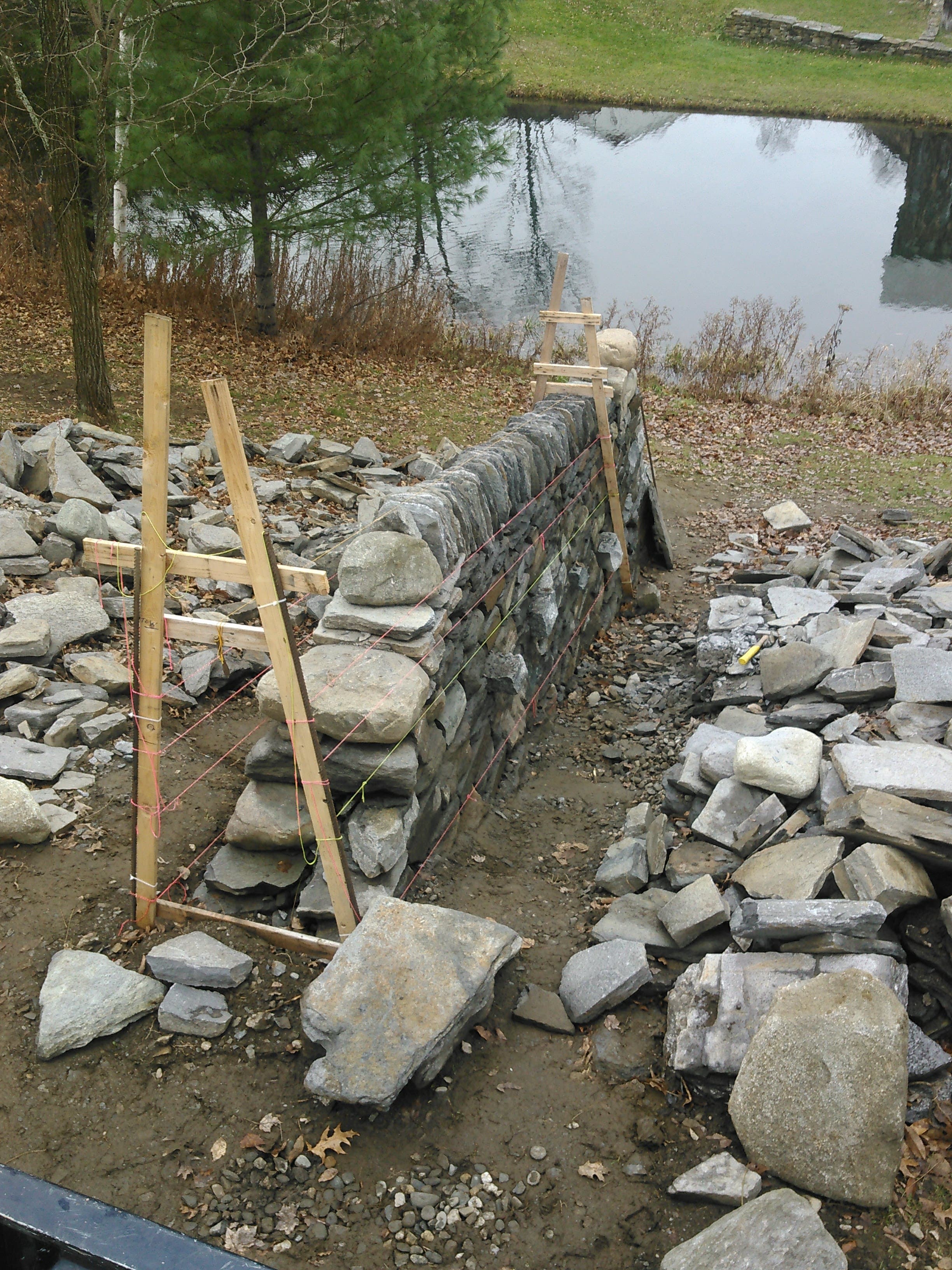 Dry stone wall construction showing large stones and temporary guides.