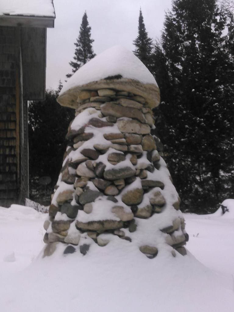 Snow-capped dry-stacked cairn in winter.